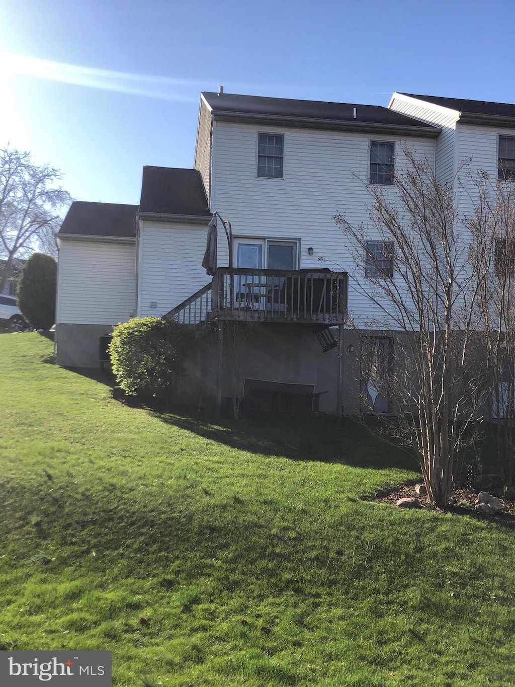 back of property with a lawn, stairway, and a deck