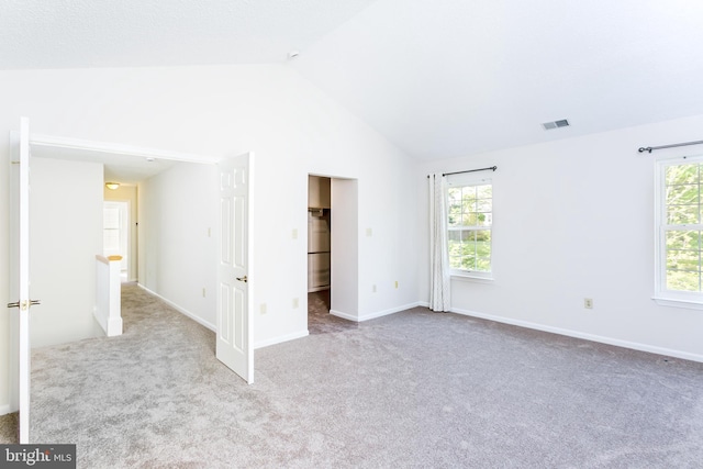 unfurnished bedroom with visible vents, lofted ceiling, baseboards, a spacious closet, and carpet
