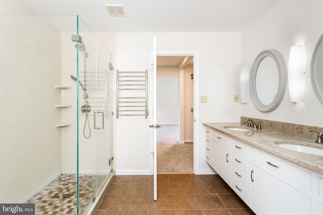 bathroom featuring double vanity, visible vents, a shower stall, and a sink