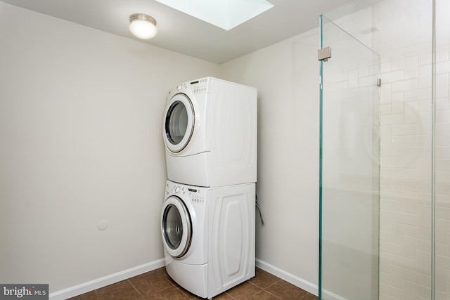laundry area with laundry area, stacked washing maching and dryer, a skylight, and dark tile patterned flooring