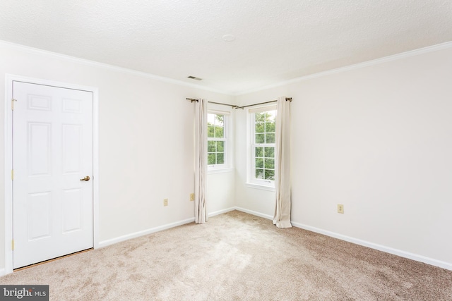 carpeted spare room featuring baseboards, ornamental molding, a textured ceiling, and visible vents