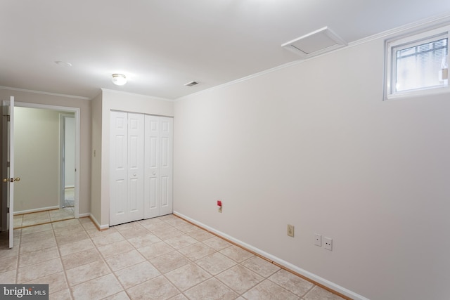 unfurnished bedroom featuring crown molding, light tile patterned flooring, baseboards, and a closet