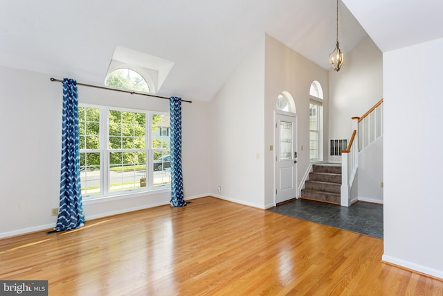 foyer featuring stairs, wood finished floors, a healthy amount of sunlight, and a chandelier