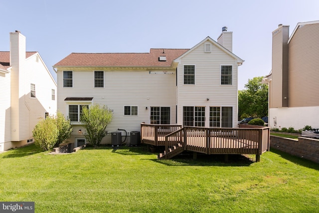 rear view of property with central air condition unit, a wooden deck, and a yard