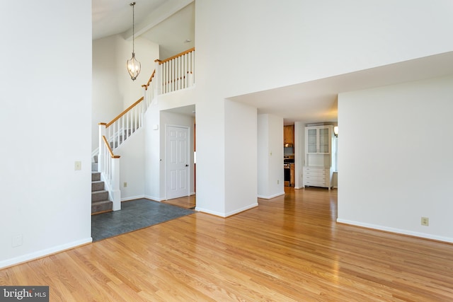 interior space with an inviting chandelier, light wood-style flooring, baseboards, and stairway