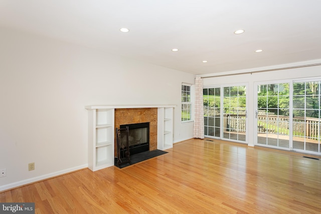 unfurnished living room featuring recessed lighting, baseboards, wood finished floors, and a fireplace