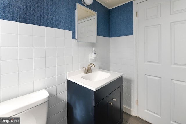 half bath with tile walls, vanity, and toilet
