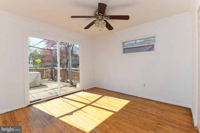 spare room featuring hardwood / wood-style flooring, baseboards, a ceiling fan, and crown molding