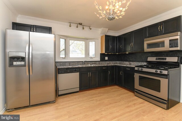 kitchen featuring dark cabinets, a chandelier, stainless steel appliances, and a sink