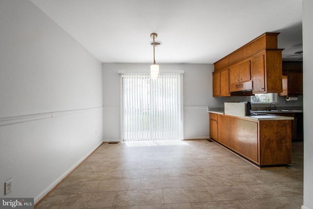 7906 Longmeadow Dr, Frederick, MD 21701 - kitchen with a sink, brown cabinets, decorative light fixtures, baseboards, and under cabinet range hood