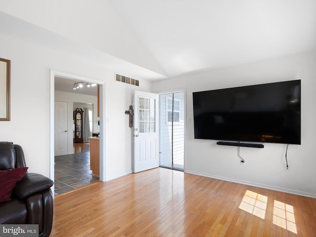 living room with lofted ceiling, wood finished floors, and visible vents