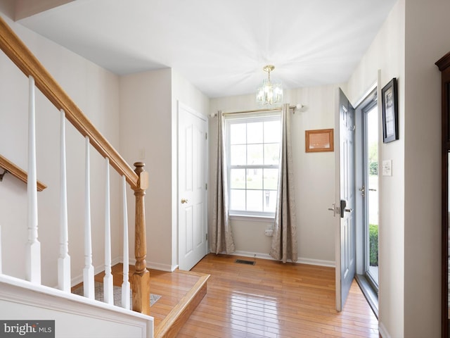 foyer featuring a healthy amount of sunlight, stairs, visible vents, and light wood-style flooring