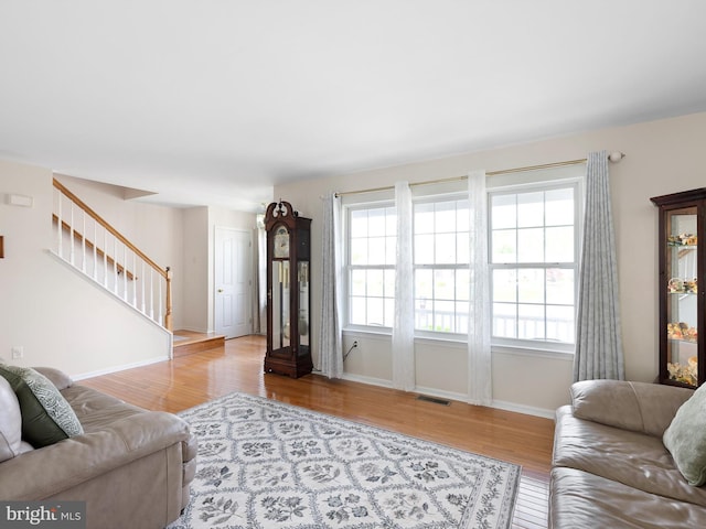living area featuring stairs, wood finished floors, visible vents, and baseboards