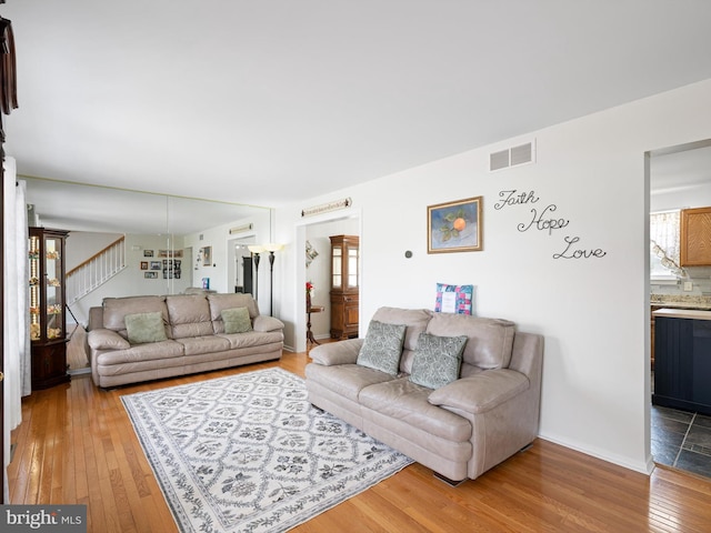 living area featuring stairs, hardwood / wood-style floors, and visible vents
