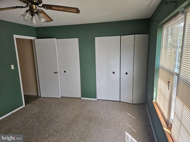 unfurnished bedroom featuring baseboards, carpet flooring, multiple closets, and ceiling fan