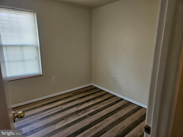 unfurnished room featuring baseboards and dark wood-style floors