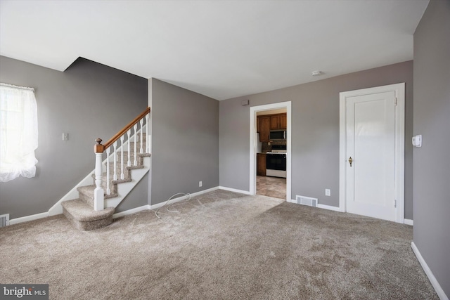 unfurnished living room with visible vents, baseboards, stairway, and carpet floors