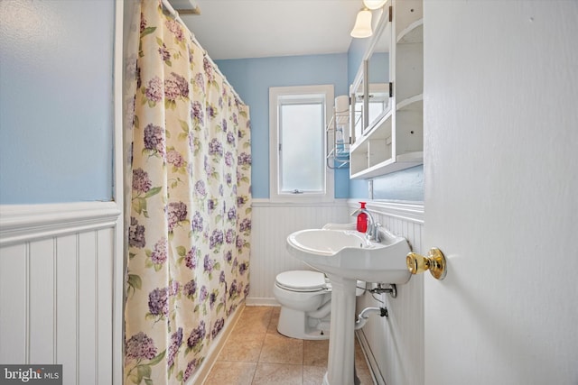 full bath featuring wainscoting, tile patterned flooring, toilet, and a shower with curtain