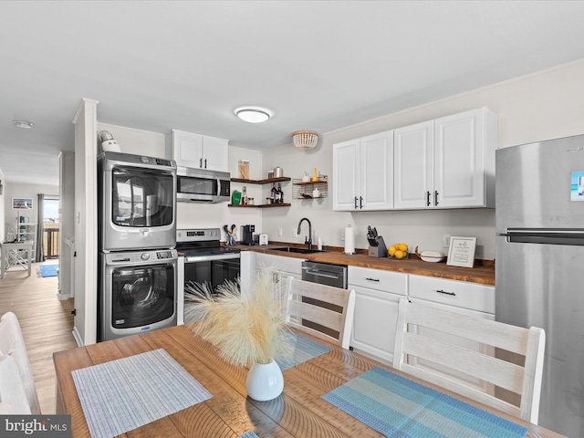 674 94th St Unit 154, Ocean City, MD 21842 - kitchen featuring a sink, butcher block counters, white cabinets, appliances with stainless steel finishes, and stacked washer and clothes dryer