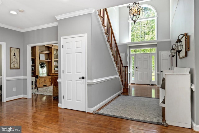 foyer entrance with stairway, baseboards, wood finished floors, and a healthy amount of sunlight