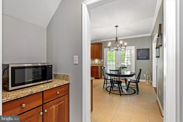 kitchen with stainless steel microwave, brown cabinets, light tile patterned flooring, and a chandelier