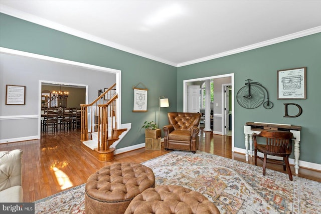 living area with an inviting chandelier, baseboards, ornamental molding, and wood finished floors