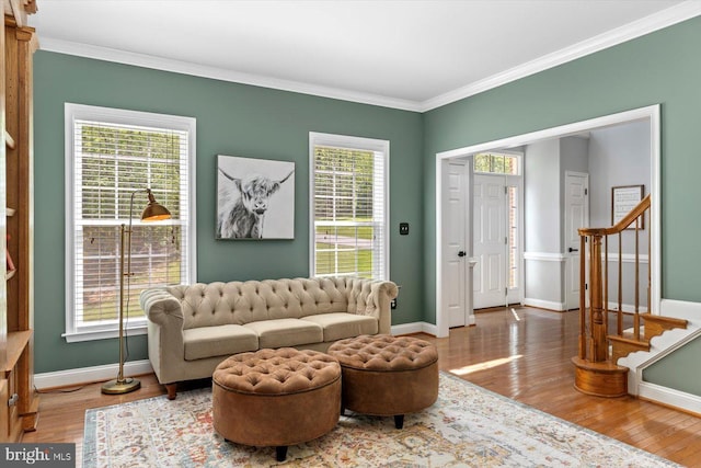 living area with baseboards, ornamental molding, and wood finished floors