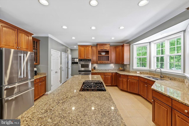kitchen featuring crown molding, glass insert cabinets, light stone counters, a sink, and appliances with stainless steel finishes