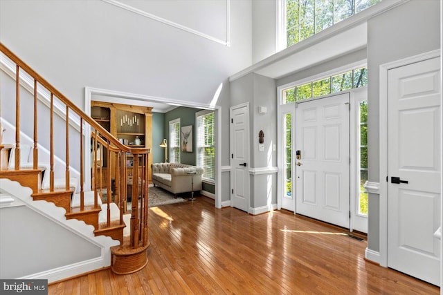 foyer featuring plenty of natural light, wood-type flooring, stairs, and a high ceiling