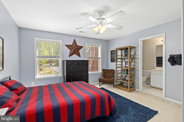 carpeted bedroom with baseboards, ceiling fan, and ensuite bath