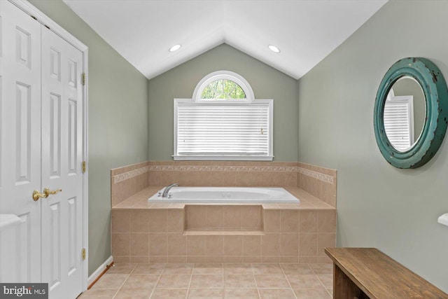 bathroom featuring tile patterned flooring, lofted ceiling, and a bath