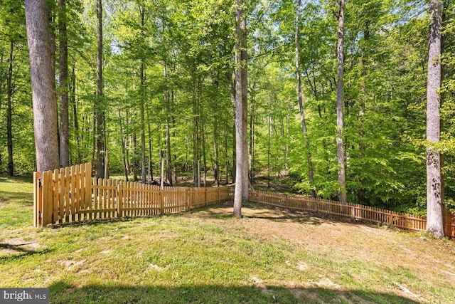 view of yard featuring fence and a wooded view