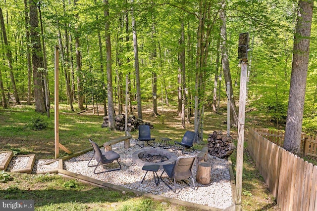 view of yard featuring fence, an outdoor fire pit, and a forest view