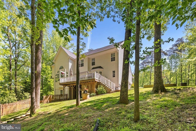 rear view of house with a yard, a deck, fence, and stairs