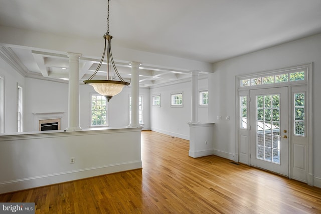 unfurnished dining area featuring ornate columns, baseboards, wood finished floors, and beamed ceiling