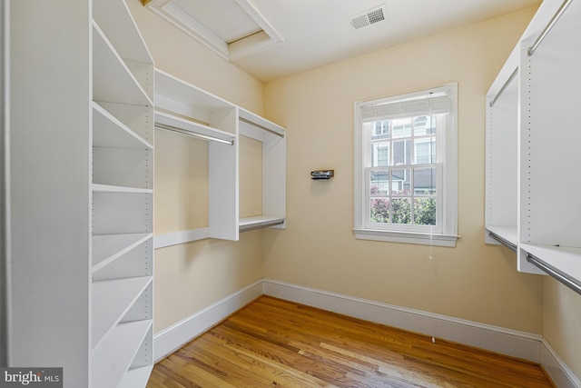 spacious closet with attic access, wood finished floors, and visible vents