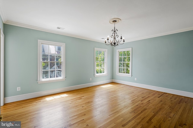 unfurnished room featuring crown molding, baseboards, wood finished floors, and a notable chandelier