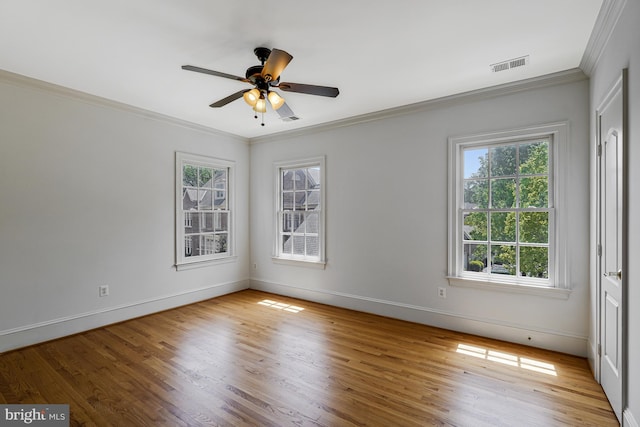 spare room with visible vents, crown molding, wood finished floors, baseboards, and a ceiling fan