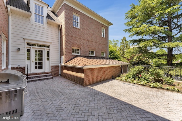 view of home's exterior featuring entry steps, fence, a patio area, and brick siding