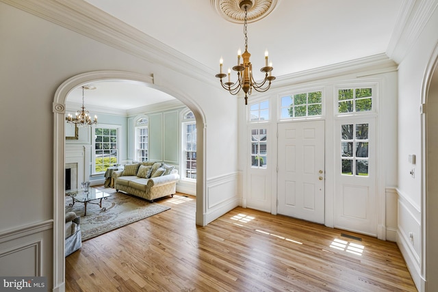 foyer with arched walkways, a chandelier, ornamental molding, and a decorative wall