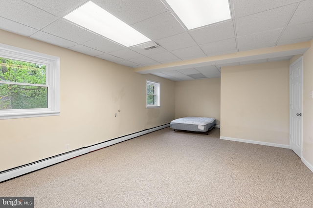 interior space with baseboard heating, carpet flooring, a drop ceiling, and visible vents