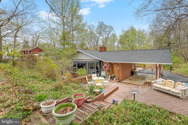 rear view of property with a chimney, a wooden deck, roof with shingles, and an outdoor hangout area