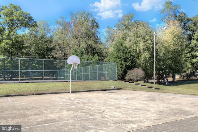view of sport court with community basketball court, fence, and a yard