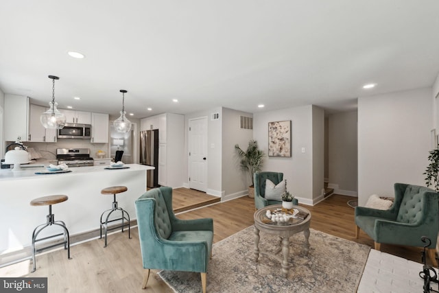 living room featuring recessed lighting, light wood-type flooring, and baseboards