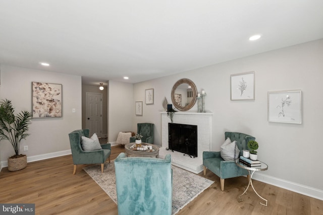 living area with baseboards, a fireplace, recessed lighting, and light wood-style floors