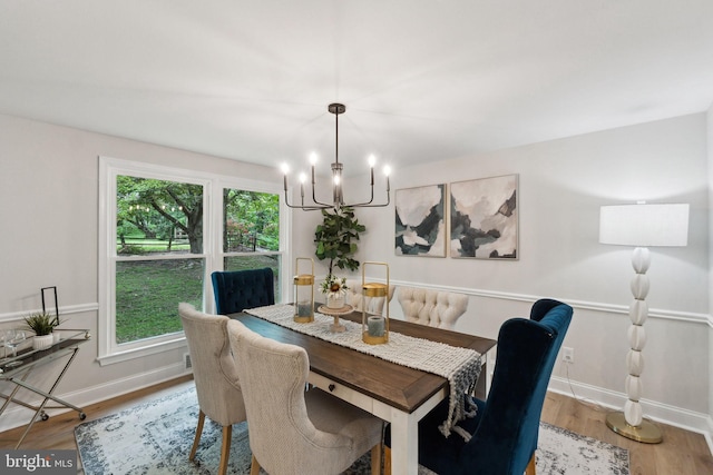 dining area featuring a chandelier, plenty of natural light, baseboards, and wood finished floors