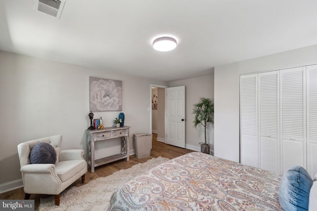 bedroom with wood finished floors, a closet, and baseboards