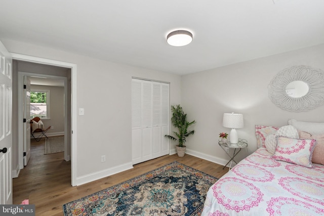 bedroom featuring wood finished floors, baseboards, and a closet