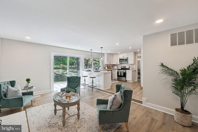 living room featuring baseboards, recessed lighting, and light wood-style floors