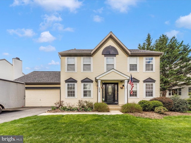 colonial home with a garage, concrete driveway, and a front yard